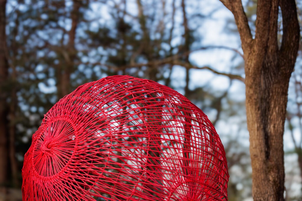 Red String sculpture installed at Rock City among the trees. 